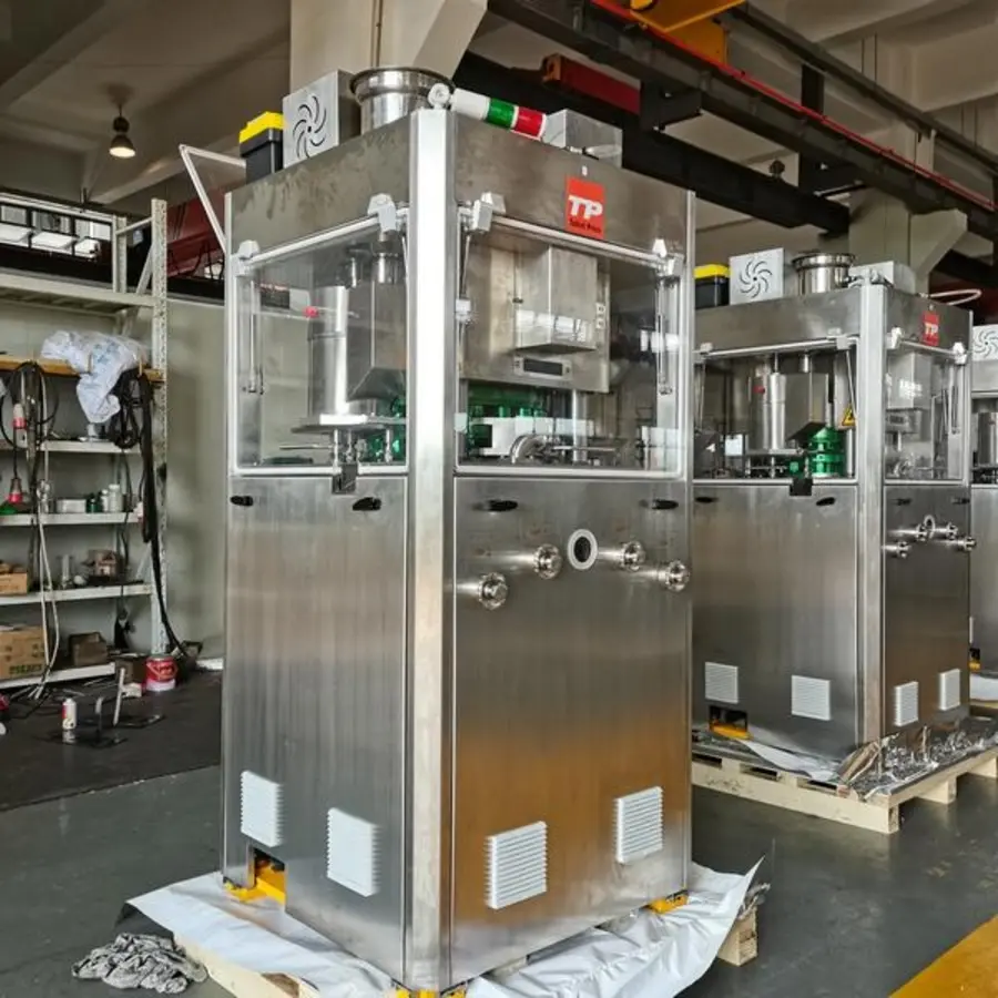 Stainless steel industrial press machines with enclosed chambers, visible tooling areas, vents, pipes, and control indicators.