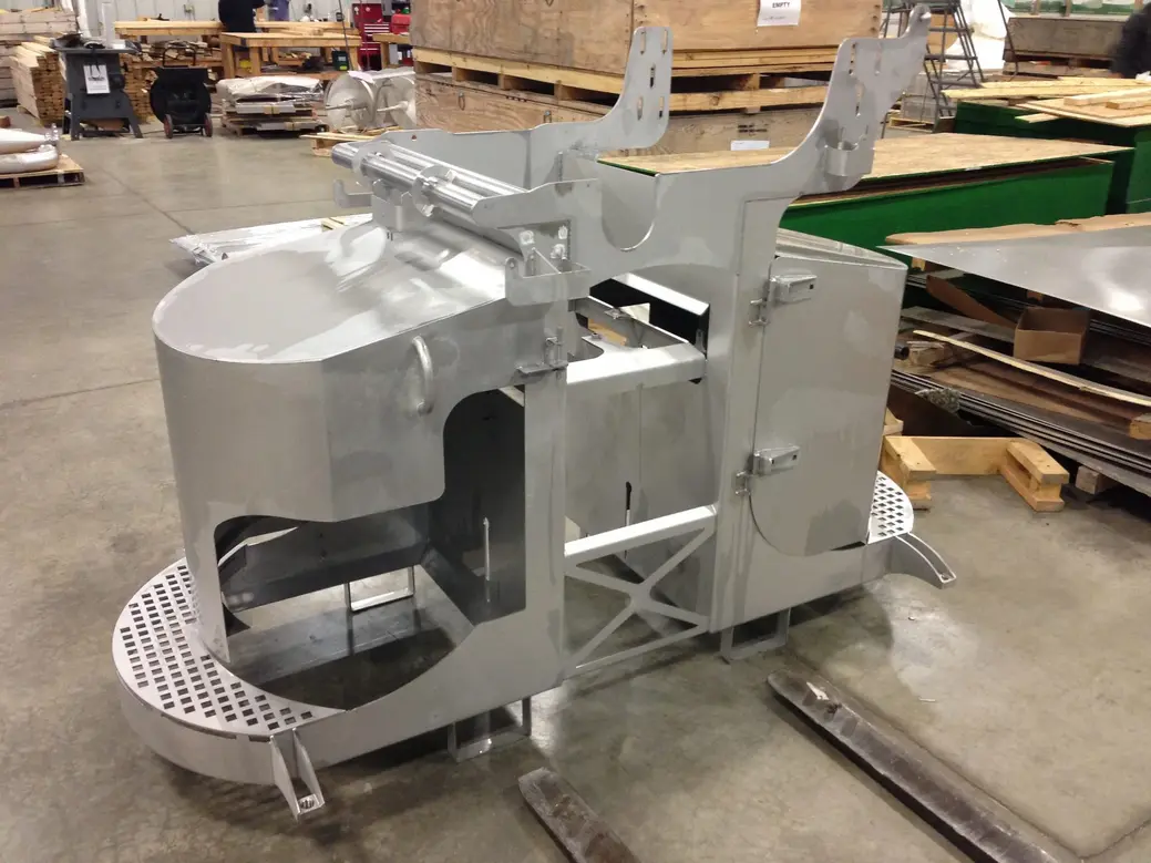 Metal food processing equipment structure with subassembly components on a factory floor.