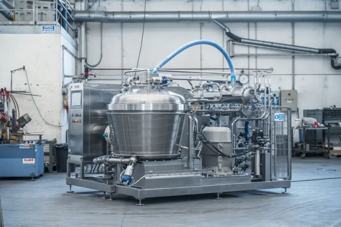 Industrial food processing equipment in a manufacturing environment with stainless steel components.