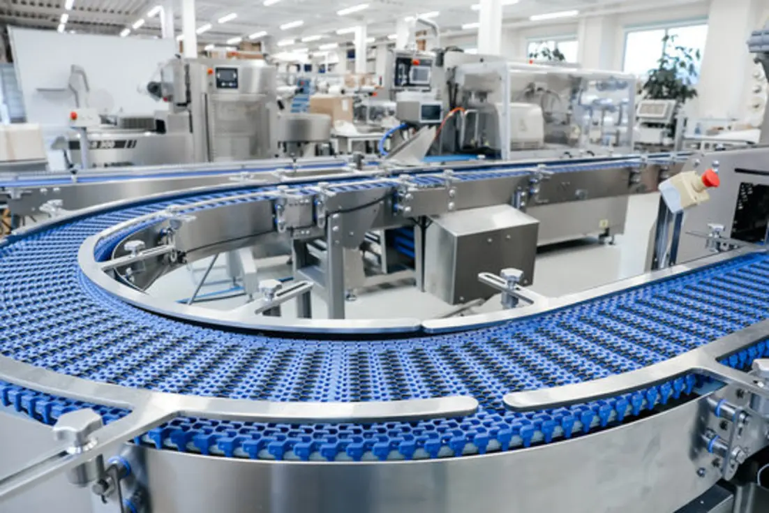 Automated food production line with interconnected blue conveyor belts, stainless steel equipment, and packaging machinery.