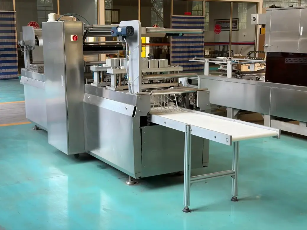 Stainless steel food packaging machinery and conveyor tables in a clean industrial processing facility.