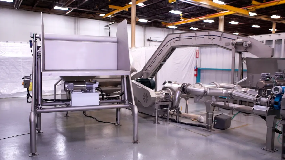 Stainless steel food processing equipment and conveyor machinery installed in a clean industrial facility.