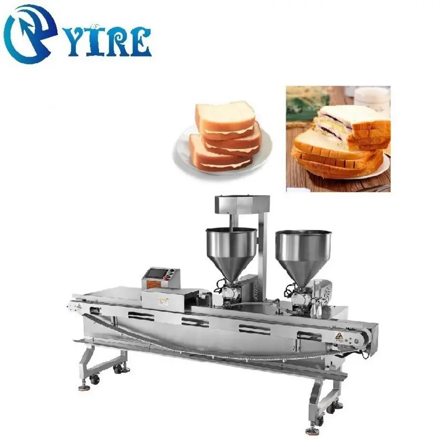 Industrial food depositing machine with dual hoppers and bread slices on a plate.