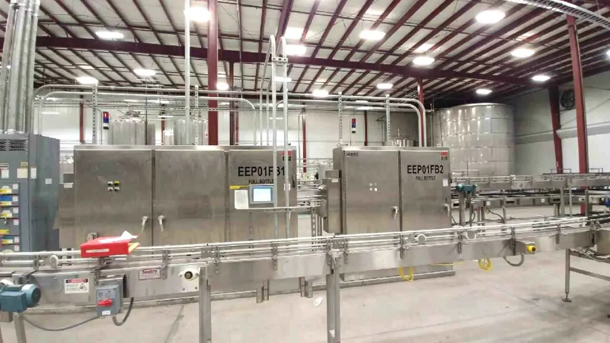 Industrial control panel setup in a food production facility with piping and machinery.