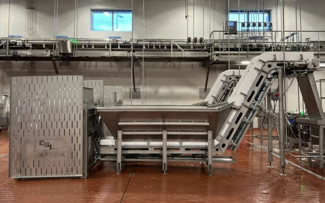 Industrial food processing equipment with a large loading area and elevated conveyor sections.