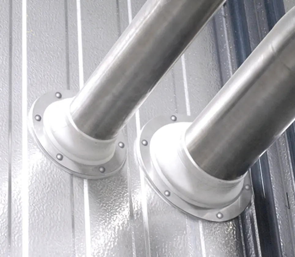 Two stainless steel pipes connected to a wall, with flanges and visible bolts.