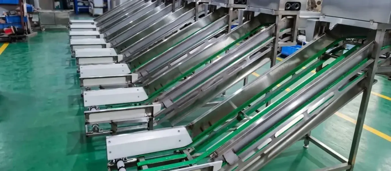 Stainless steel food processing equipment with inclined conveyor sections in a maintenance setting.