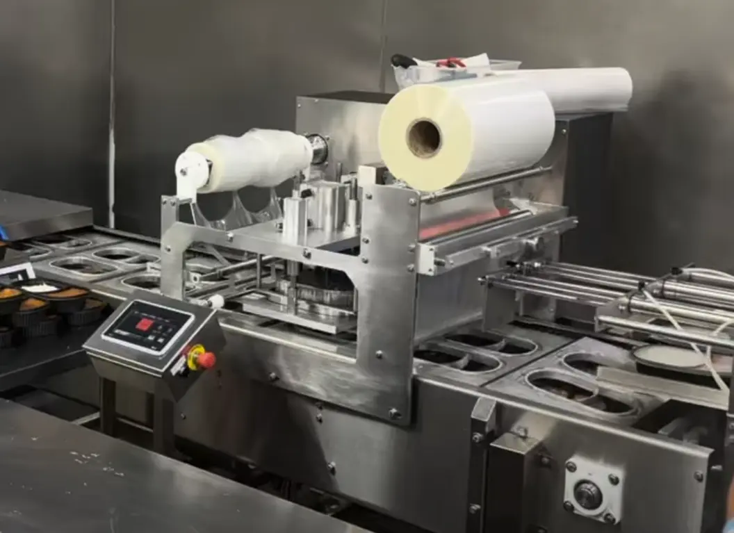 Sealing machine with a roll of film and touchscreen control in a food production line.